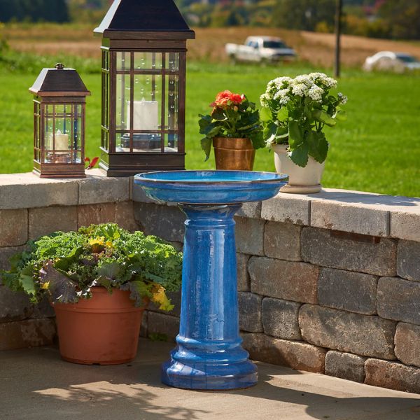 Blue birdbath with potted plants on a stone ledge outdoors