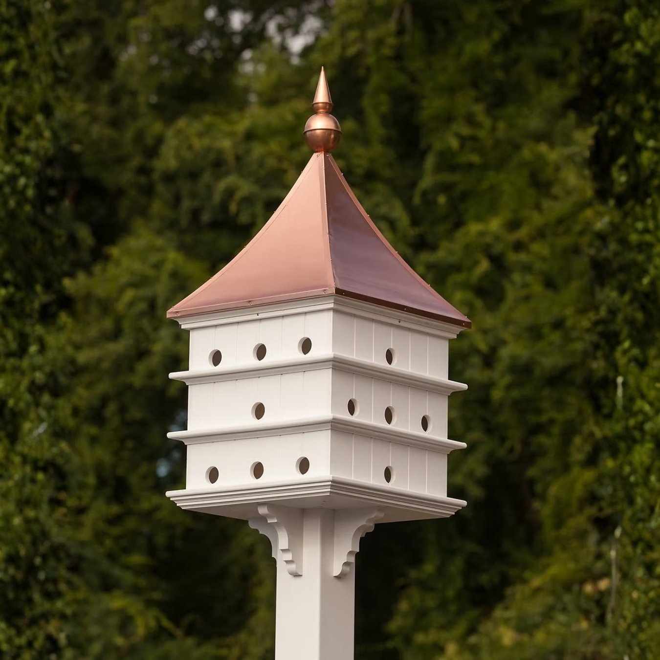 Grand estate Purple Martin birdhouse with a copper roof against a green foliage background