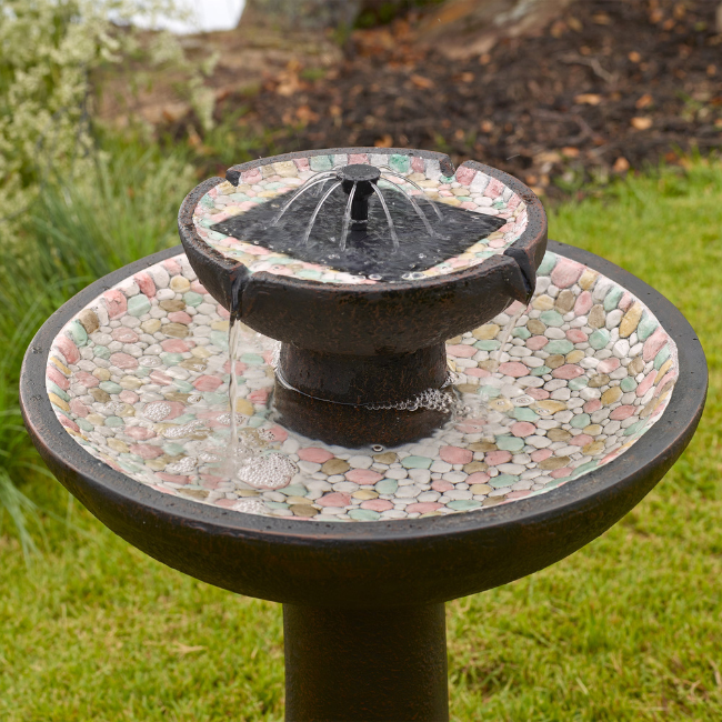 Close-up of Solar Pebble Stream Fountain with water flowing over hand-painted pebbles, powered by solar energy for an eco-friendly outdoor water feature.