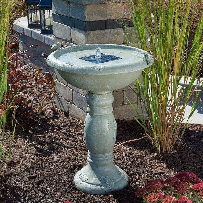 Tall Solar Fountain Bird Bath in backyard with brick landscaping and plants in the background
